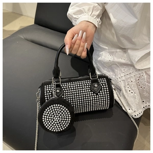 Detail of black cylinder bag featuring silver studs, chain strap and mini round pouch