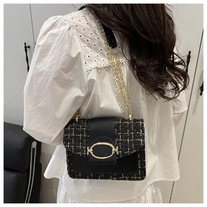 Nahaufnahme der schwarz-goldenen Tweed-Textur und der eleganten Metallschnalle der Tasche