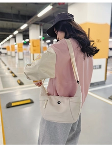 Sac croissant en nylon crème avec bandoulière réglable et poche zippée porté par mannequin