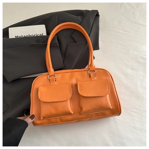 Detail view of the orange shoulder bag showing dual front flap pockets and silver hardware