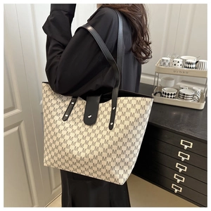Detail of Monogram tote bag with black leather handles and silver rivet buckle closure