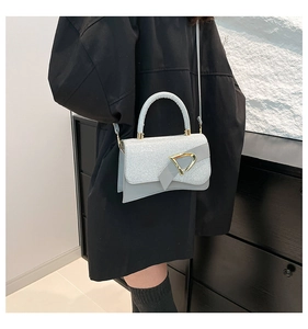 Close-up of glitter finish light blue handbag with gold D-shaped metal buckle and curved base
