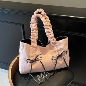 Pink nylon tote bag with ruffled handles and black ribbon bows on a stylish chair
