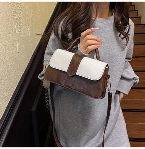 Détail du sac à main bicolore en cuir marron et blanc avec une breloque métallique élégante