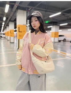 Détail du blouson d'université rose et crème brodé avec sa sacoche en nylon assortie