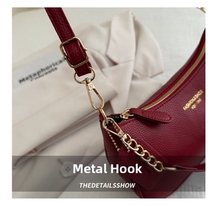 Detail of red lychee leather bag featuring gold hooks and Fashion & Bags gold text