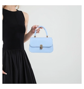 Close-up of light blue saddle bag with gold metal buckle and smooth leather texture
