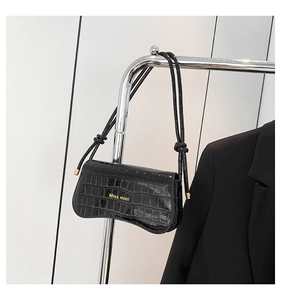 Detail of glossy black crocodile pattern leather shoulder bag with curved bottom