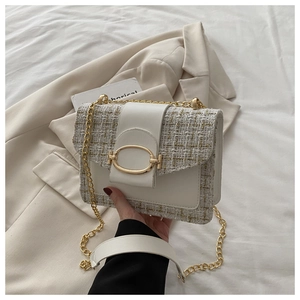 Details der eleganten beige Tweed-Umhängetasche mit Goldkette und ovalem Metallschloss