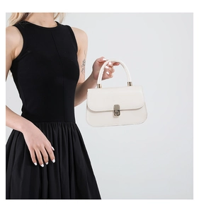 French style cream leather crossbody bag with gold lock shown on a model in black dress