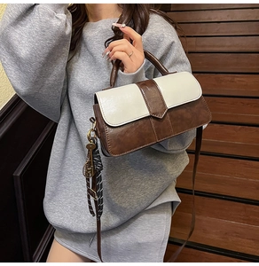 Détail du sac à bandoulière bicolore avec design color-block et breloque en ruban noué