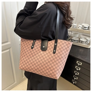 Detail of pink tote bag with M-pattern print, black leather straps and magnetic closure