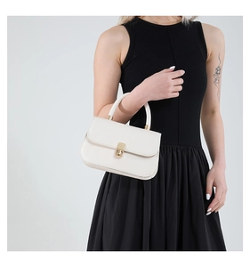 Close-up of white leather handbag with golden lock detail worn by model in black dress