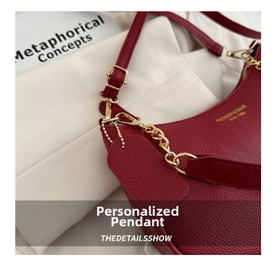 Detail of burgundy pebbled leather handbag featuring gold chain and fashion bag logo