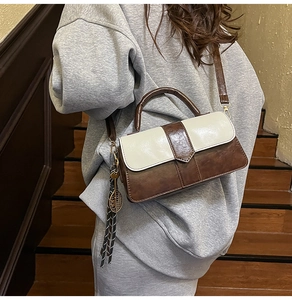 Détail du sac bandoulière bicolore avec breloque raquette de tennis sur l'escalier