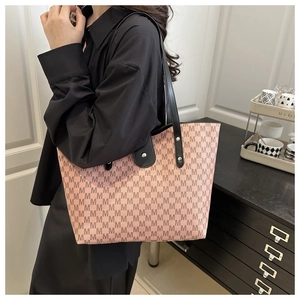 Close-up of pink tote bag with black M pattern, shoulder strap, and metal rivet details