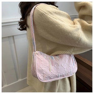 Close-up of pink baguette shoulder bag with diamond embossing and colorful stripe detail