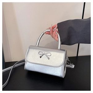 Close-up of metallic silver handbag with pleated texture and metal bow detail