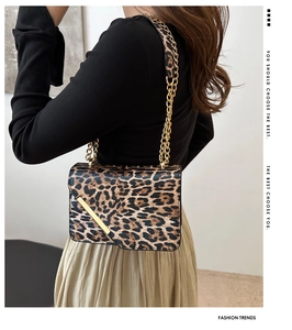 Detailed view of leopard print shoulder bag with gold chain strap on a female model