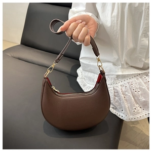 Detail of crescent shoulder bag featuring lychee grain leather and vibrant red lining