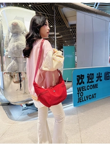Sac croissant rouge en nylon porté en bandoulière avec sangle réglable en décor urbain