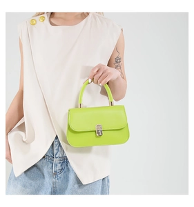 Detail of a bright green leather saddle bag with metallic buckle closure and handle