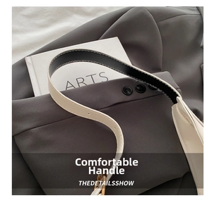 Detail of white leather shoulder strap with black edge finishing on a grey blazer