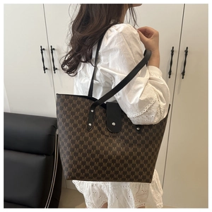 Detail of large tote bag showing M-letter print, black straps and silver metal rivets