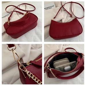 Detail view of burgundy lychee leather baguette bag with gold zipper and hardware