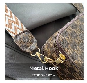 Detail of golden metal hook on brown monogram crossbody bag with woven strap