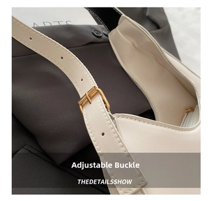 Detail of adjustable golden metal buckle and textured leather strap on a crescent bag