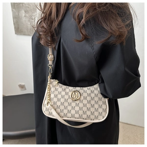 Detail of beige monogram shoulder bag with gold M logo and decorative metal chain
