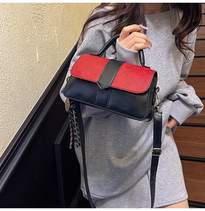 Détail du sac à main bicolore rouge et noir avec foulard décoratif sur la poignée