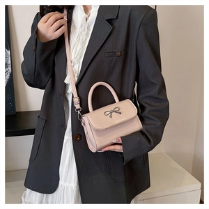 Detail view of pink structured crossbody bag with silver bow buckle on model dress