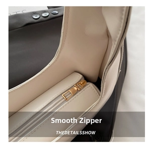 Macro detail of high-quality smooth golden metal zipper and cream leather texture on the bag
