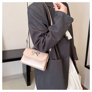 Detail of pink mini handbag with silver bow buckle worn as a crossbody bag