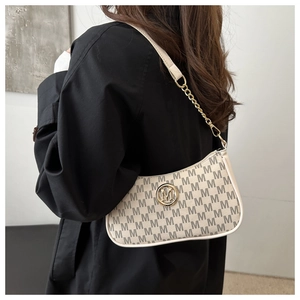 Close-up of crescent underarm bag with monogram pattern and gold metal M logo detail