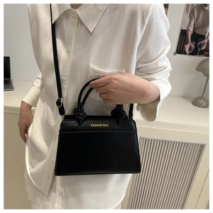 Detail of knot handle and gold 'FASHION BAG' print on black leather crossbody bag