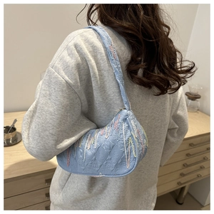 Detail of light blue nylon crossbody bag with quilted monogram and floral embroidery texture