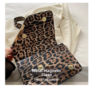 Detail of golden magnetic snap closures on the leopard print shoulder bag flap
