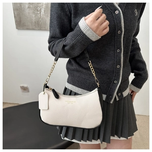 Detail der weißen Tasche aus Lychee-Leder mit Kontrastkanten und goldener Kette