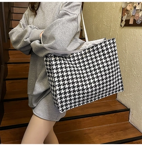 Lifestyle shot of large houndstooth tote bag with white shoulder straps on casual model