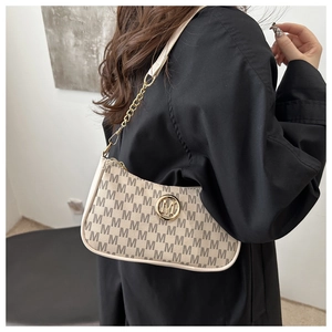 Close-up of beige crescent bag with grey letter print and gold chain strap on model