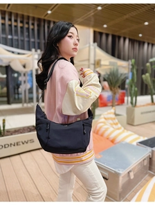 Détail d'un sac demi-lune en nylon noir avec poches latérales et bandoulière réglable