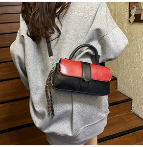 Détail du sac bandoulière bicolore rouge et noir avec pendentif raquette de tennis