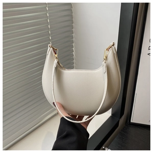 Detail der weißen Halbmond-Tasche mit Lychee-Leder-Textur und goldenem Metallverschluss
