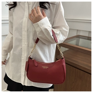 Close-up of wine red litchi texture handbag with gold chain strap and zipper detail