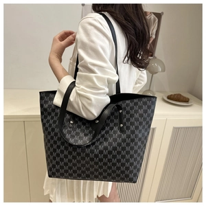 Detailed close-up of large tote bag with M-pattern print and silver stud accents