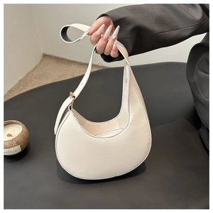 Close-up of a cream white minimalist hobo bag with adjustable strap and silver metal buckle