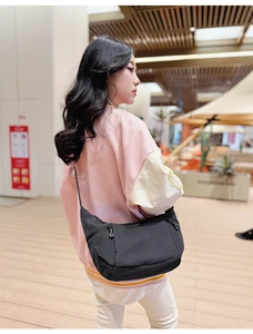 Détail du sac bandoulière en nylon noir avec poches zippées et sangle réglable